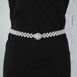 Detail of beaded pearl waist belt with sparkling rhinestone buckle on black dress