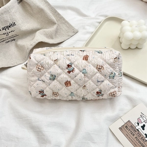 Detailed texture of quilted cream pouch with cute bear prints and zipper closure