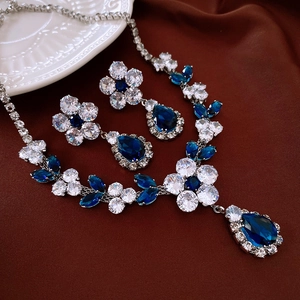 Detail of luxury teardrop jewelry set with blue and clear crystals on silk fabric