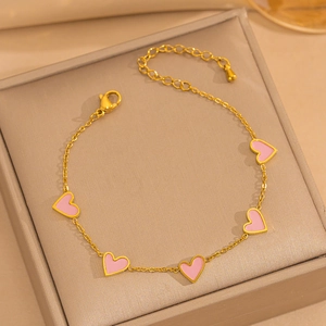 Detail of gold bracelet with pink enamel heart charms and lobster clasp on display