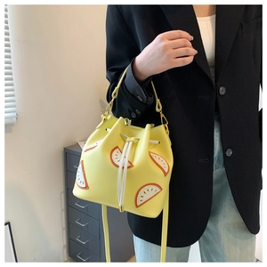 Detail showing yellow fruit bucket bag with drawstring and orange slice pattern on model
