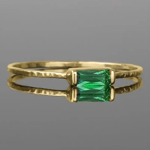 Detailed macro view of gold hammered ring band with rectangular green emerald gemstone