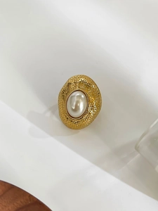 Detailed macro view of the 18k gold vintage hammered texture and oval pearl inlay