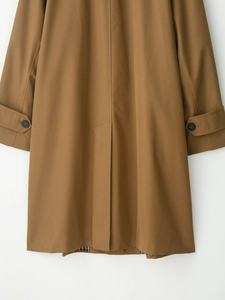 Detail of the back slit and adjustable cuff straps on the brown mid-length trench coat