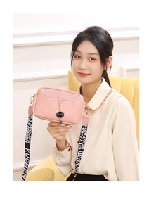 Detail of pink woven crossbody bag with black cat pendant and letter printed strap