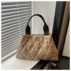 Detail of khaki quilted tote bag with soft diamond stitching and black straps
