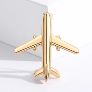 Golden airplane metal brooch pin displayed on white props for elegant suit accessories