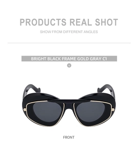 Close-up of cat-eye sunglasses with glossy black frames and gold-trimmed grey lenses