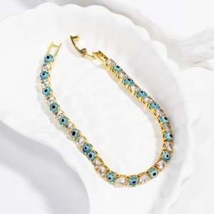 Macro detail of gold-plated evil eye tennis bracelet with 4mm blue and white cubic zirconia