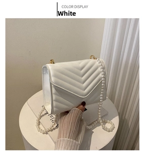 Close-up of white quilted leather crossbody bag with elegant pearl chain strap detail