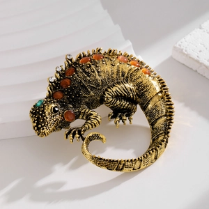 Vintage golden chameleon brooch with brown rhinestones and green gem eyes on white background