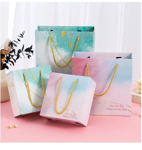 Detail of pink and marble gift bags with golden rope handles for wedding and parties