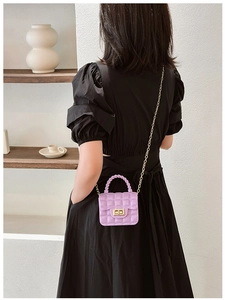 Close-up of mini purple jelly bag with quilted pattern and gold chain on a model