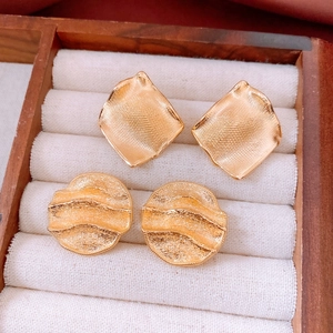Detail view of 18k gold plated round wrinkled earrings in a wooden jewelry box