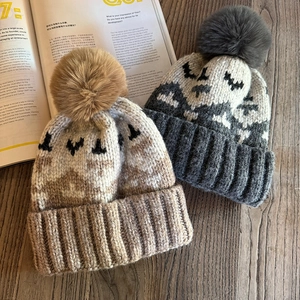 Winter beanie with faux fur pom pom featuring Nordic pixel knit pattern on wood background