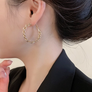 Gros plan d'élégantes créoles tressées dorées portées par un mannequin de profil