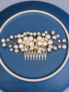 Close-up of golden bridal hair comb with elegant white pearls and sparkling rhinestones