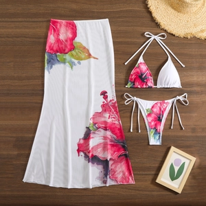 Detail view of floral three-piece bikini set with matching mesh maxi cover-up on wood background