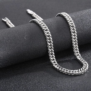 Close-up of polished silver cuban link chain necklace on a minimalist jewelry stand