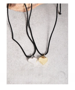 Close-up of polished silver and gold heart pendants with minimalist black cords