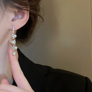 Detail of silver long tassel earrings with white pearls and zircons worn by model