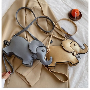 Close-up of golden and grey elephant crossbody bags on a beige trench coat background