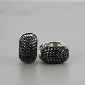 Macro shot of curved hoop earrings with micro-paved black zircon stones and silver metal