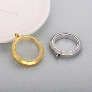 Close-up of gold and silver round locket pendants with glass panels on grey background