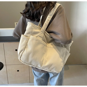 Détail d'un sac fourre-tout en velours côtelé beige avec texture côtelée et poche frontale
