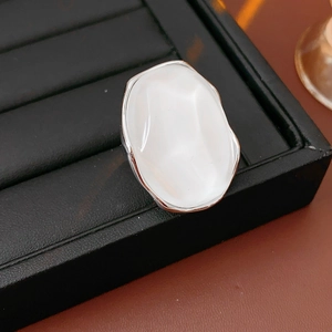 Close-up of minimalist silver ring with irregular white resin inlay on a black display