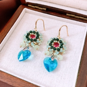 Close-up of handmade ethnic bead earrings with blue heart pendant in a jewelry box