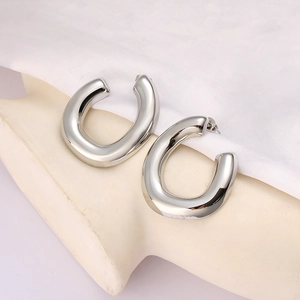 Polished silver U-shaped hoop earrings displayed on a white textured fabric background