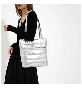 Detail of silver puffer tote bag with quilted texture and metallic finish on shoulder