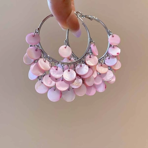 Close-up of silver hoop earrings with pink shell petal tassels for a beach vacation look