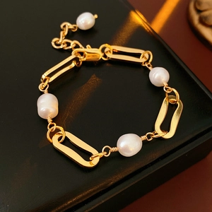 Detail of gold-plated chain bracelet with freshwater pearls on black leather box