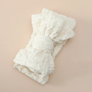 Macro view of creamy white oversized double-layered bow headband in crinkled fabric