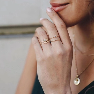Detail of stacked gold rings with white zircon stones worn on model's hand