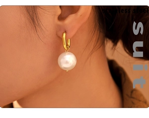 Close-up of elegant gold stainless steel U-shaped hoop earring with large white pearl