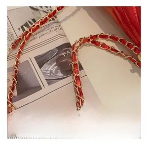 Detailed macro shot of red patent leather texture and gold-tone metal chain link strap