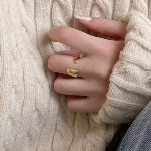 Detail of adjustable gold geometric ring on hand with minimalist winter knitwear styling