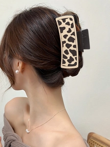 Close-up of a large matte cow print claw clip on hair with soft natural lighting