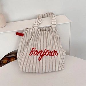Detail of striped canvas tote bag with Bonjour embroidery and red side ribbon
