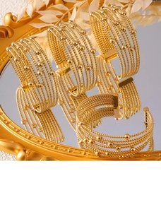 Macro view of gold beaded multilayer cuff bracelet on a vintage mirror surface