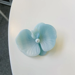 Elegant light blue orchid petal hair clip with white pearl center on a white surface