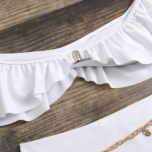 Détail de bikini blanc à volants avec boucle argentée et chaîne dorée à pendentif coquillage