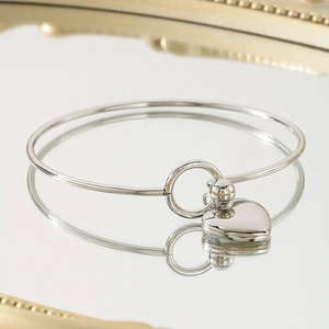 Detailed view of polished silver heart pendant on a minimalist stainless steel bangle