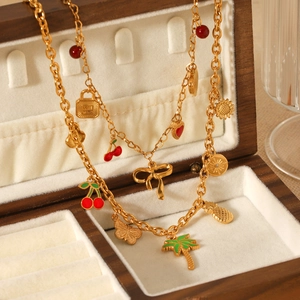 Gold stainless steel necklace featuring cherry, palm tree and sun charms in a wooden box