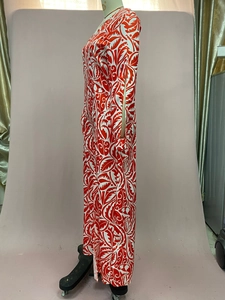 Détail d'une robe longue à imprimé feuilles rouge et blanc avec fente latérale haute sur mannequin