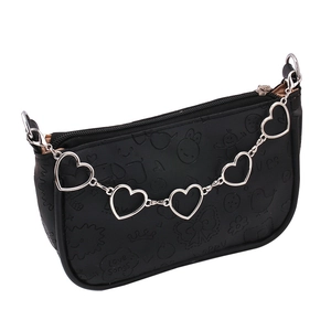 Detail of black mini bag with embossed cartoon patterns and silver heart chain strap