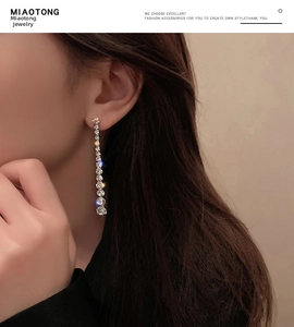 Detailed view of long silver tassel earrings with sparkling white crystal drops on model